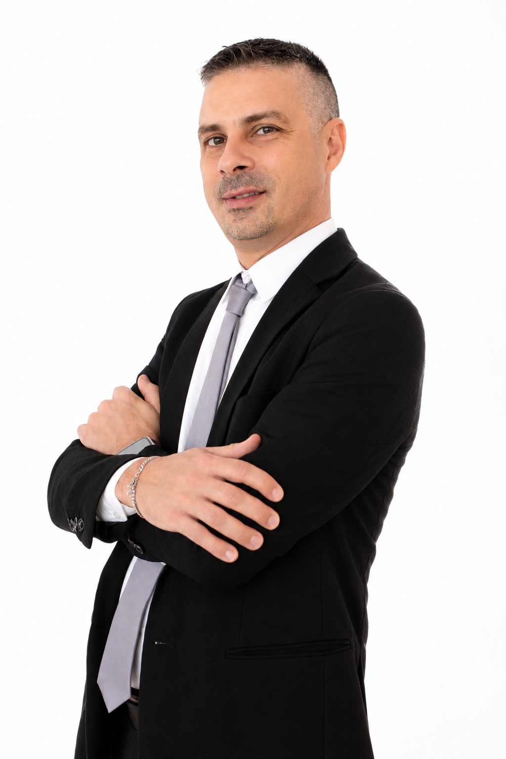 Corporate business portrait of a professional in a black suit and grey tie with folded arms against a white background.